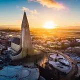 Zachód słońca nad Hallgrímskirkją, symbolem stolicy Islandii. Miasto w zimowej szacie, z ośnieżonymi dachami i ulicami.