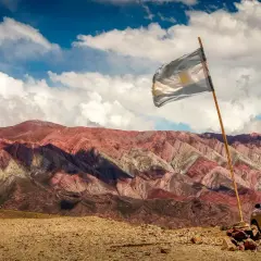 Kolorowe góry w Argentynie, flaga powiewa na wietrze. Czy Argentyna jest bezpieczna? Tak, podróżowanie po Argentynie jest bezpieczne, zwłaszcza w takich malowniczych miejscach.