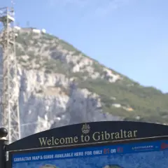 Tablica "Welcome to Gibraltar" przed skalistym zboczem. Czy Gibraltar to państwo? Mapa i przewodnik dostępne za 1 funta lub 1 euro.