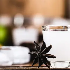 Mętny arak w szklance, obok gwiazdka anyżu i kostki lodu.