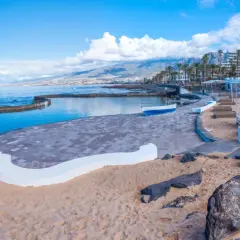 Piękny widok na Playa de las Américas z basenem, plażą i kolorowymi budynkami w tle.