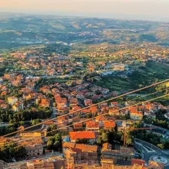 Widok na San Marino z góry, z dachami domów i zielonymi wzgórzami. Czy do San Marino potrzebny jest paszport? Nie, wystarczy dowód osobisty.