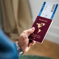 Dłoń trzyma paszport i bilet lotniczy. Czy na Cypr trzeba paszport? Tak, do podróży na Cypr potrzebny jest paszport.