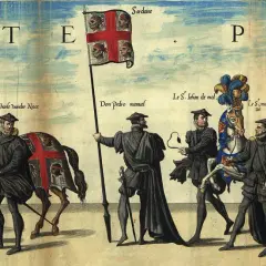 Uroczysty pochód z flagą Sardynii, przedstawiającą głowy Maurów. Postacie w historycznych strojach, jeden z nich niesie sztandar.