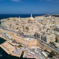 Malta stolica, Valletta, rozciąga się wzdłuż wybrzeża, z dominującą kopułą katedry i fortyfikacjami.