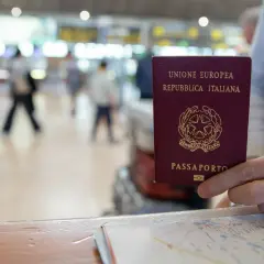 W podróży do Irlandii, czy do Irlandii potrzebny jest paszport? W ręku włoski paszport, na tle lotniska.