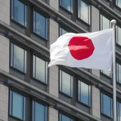 Flaga Japonii powiewa przed nowoczesnym budynkiem. Japonia liczba ludności to ponad 125 milionów osób.