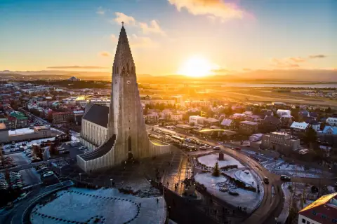 Zachód słońca nad Hallgrímskirkją, symbolem stolicy Islandii. Miasto w zimowej szacie, z ośnieżonymi dachami i ulicami.