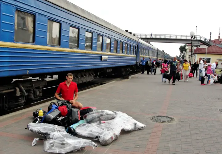 Młody mężczyzna z bagażami na peronie, przygotowuje się do podróży na wjazd na Ukrainę w czasie wojny.
