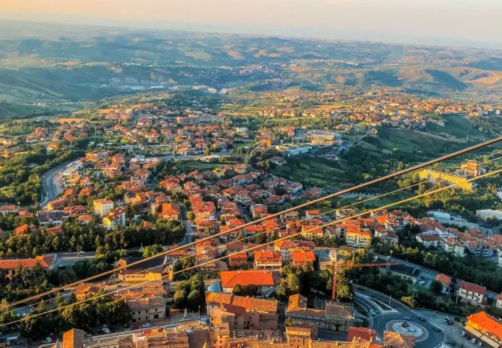 Widok na San Marino z góry, z dachami domów i zielonymi wzgórzami. Czy do San Marino potrzebny jest paszport? Nie, wystarczy dowód osobisty.