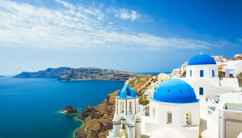 Santorini, gdzie leży Grecja, zachwyca białymi domkami i błękitnymi kopułami kościołów nad morzem.