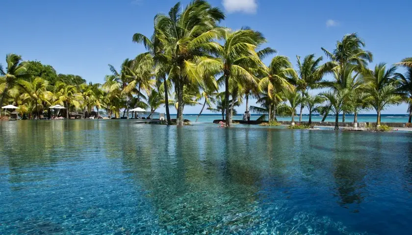 Basen z turkusową wodą i palmami na tle błękitnego nieba. Idealne miejsce na relaks, nawet podczas mauritius pora deszczowa.