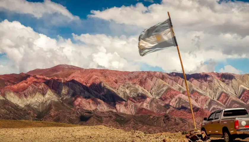Kolorowe góry w Argentynie, flaga powiewa na wietrze. Czy Argentyna jest bezpieczna? Tak, podróżowanie po Argentynie jest bezpieczne, zwłaszcza w takich malowniczych miejscach.