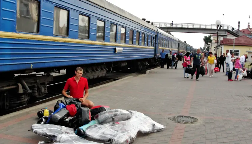 Młody mężczyzna z bagażami na peronie, przygotowuje się do podróży na wjazd na Ukrainę w czasie wojny.