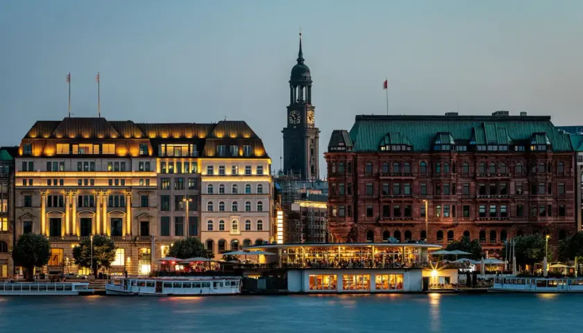 Wieczorny widok na port w Hamburgu, gdzie tętni życie, a budynki oświetlone tworzą malowniczy krajobraz.