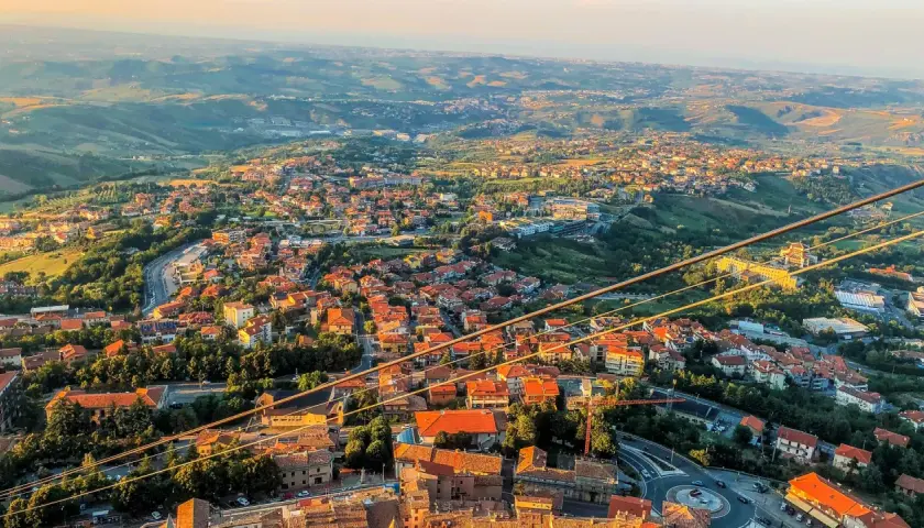 Widok na San Marino z góry, z dachami domów i zielonymi wzgórzami. Czy do San Marino potrzebny jest paszport? Nie, wystarczy dowód osobisty.