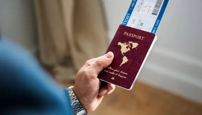 Dłoń trzyma paszport i bilet lotniczy. Czy na Cypr trzeba paszport? Tak, do podróży na Cypr potrzebny jest paszport.