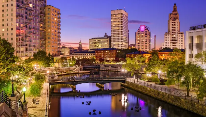 Wieczorny widok na Providence, stolicę najmniejszego stanu USA, Rhode Island. Rzeka otoczona budynkami i zielenią.