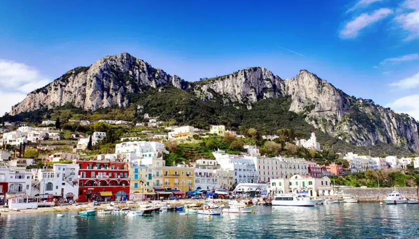 Kolorowe domy nad zatoką, góry w tle. Widok na urokliwy port na wyspie Capri.