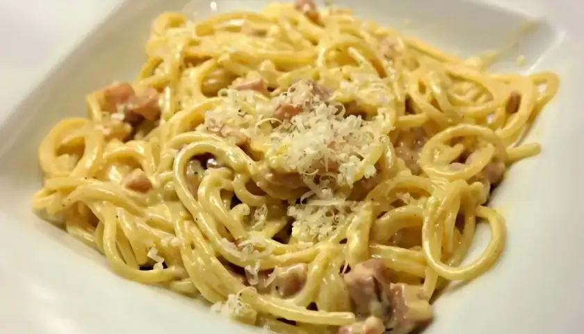 Pyszne spaghetti carbonara z kawałkami boczku i startym parmezanem. Idealna odpowiedź na pytanie: jaka śmietana do carbonary?