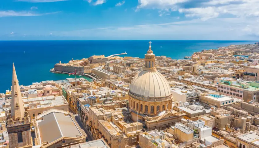 Malta w marcu: słoneczna pogoda nad Vallettą, z widokiem na morze, kopułę katedry i zabytkowe budynki.