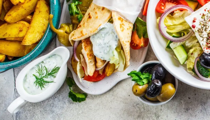 Pyszne greckie danie: gyros w picie, frytki, sałatka grecka z fetą i oliwkami, sos tzatziki.
