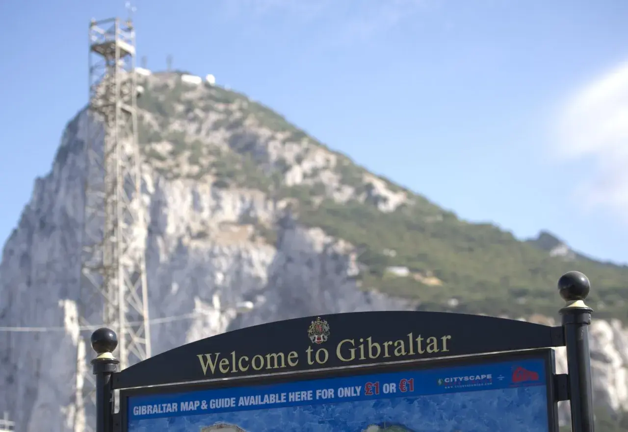 Tablica "Welcome to Gibraltar" przed skalistym zboczem. Czy Gibraltar to państwo? Mapa i przewodnik dostępne za 1 funta lub 1 euro.