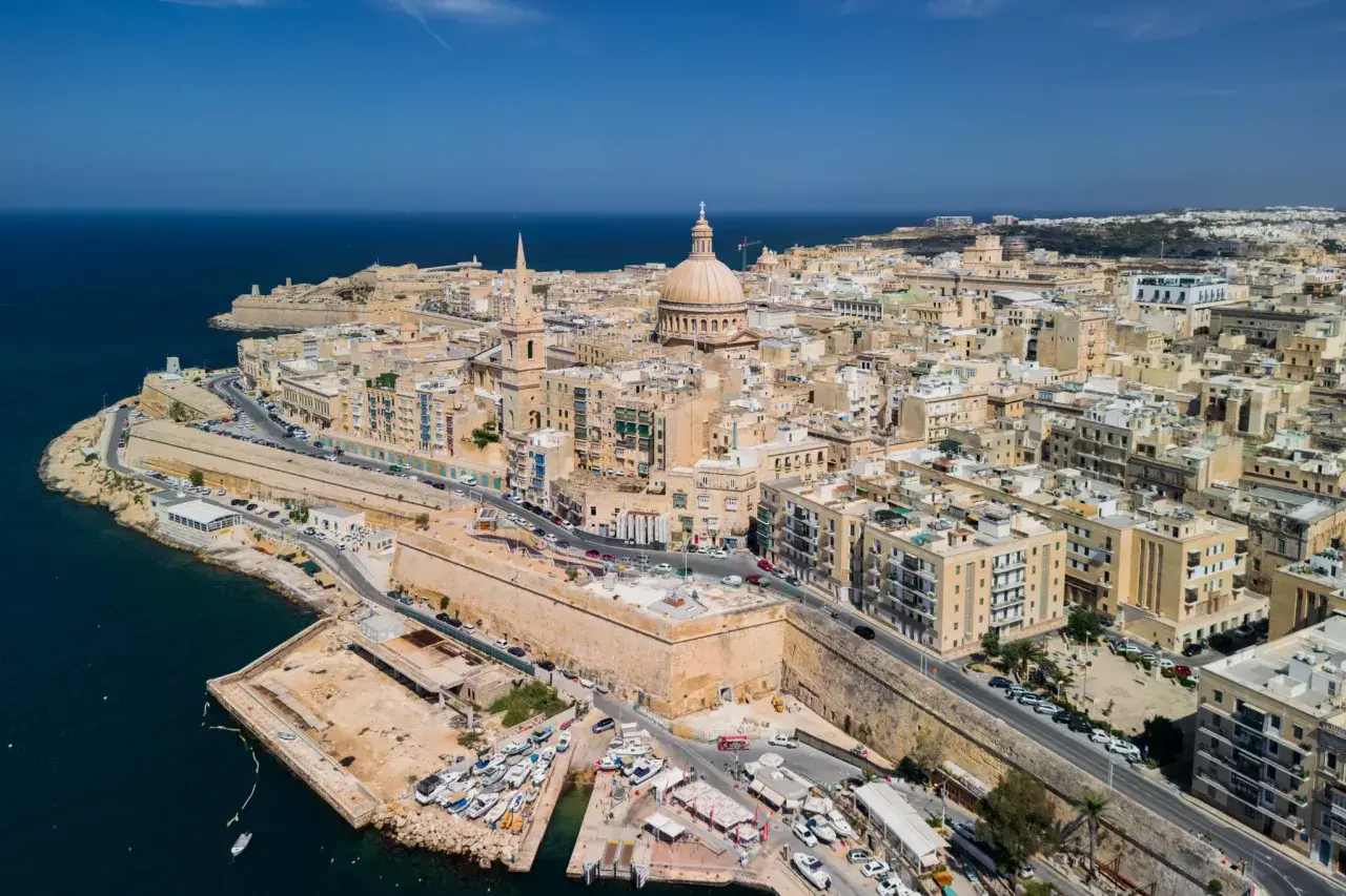 Malta stolica, Valletta, rozciąga się wzdłuż wybrzeża, z dominującą kopułą katedry i fortyfikacjami.