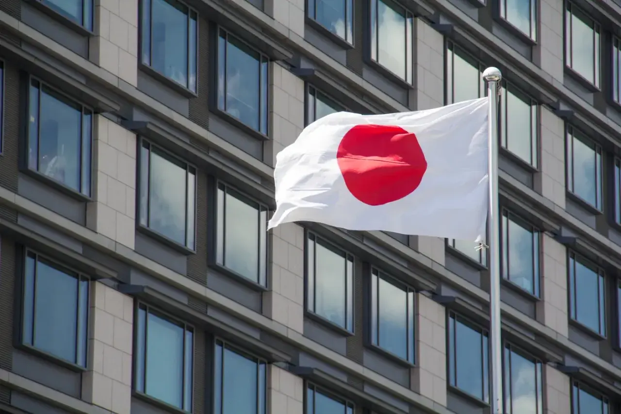 Flaga Japonii powiewa przed nowoczesnym budynkiem. Japonia liczba ludności to ponad 125 milionów osób.