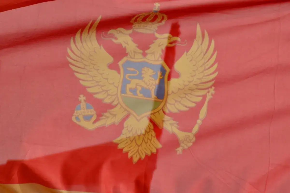 Flaga Czarnogóry z dwugłowym orłem, koroną i tarczą herbową. Symbol dumy narodowej.