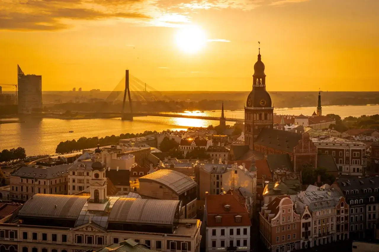 Zachód słońca nad Rygą, stolicą Łotwy. Widok na rzekę, most i zabytkowe budynki.