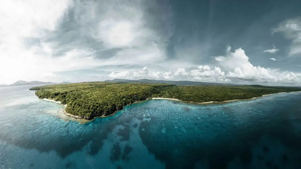Zielone wyspy Vanuatu otoczone turkusową wodą, z widocznymi rafami koralowymi pod powierzchnią.